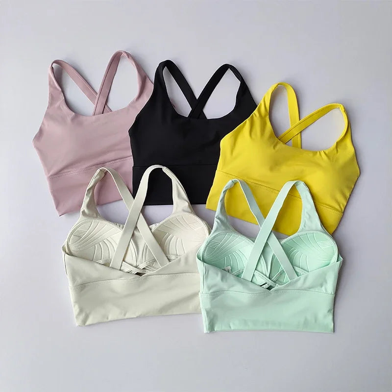 Set of five sports bras in various colors on a light gray background