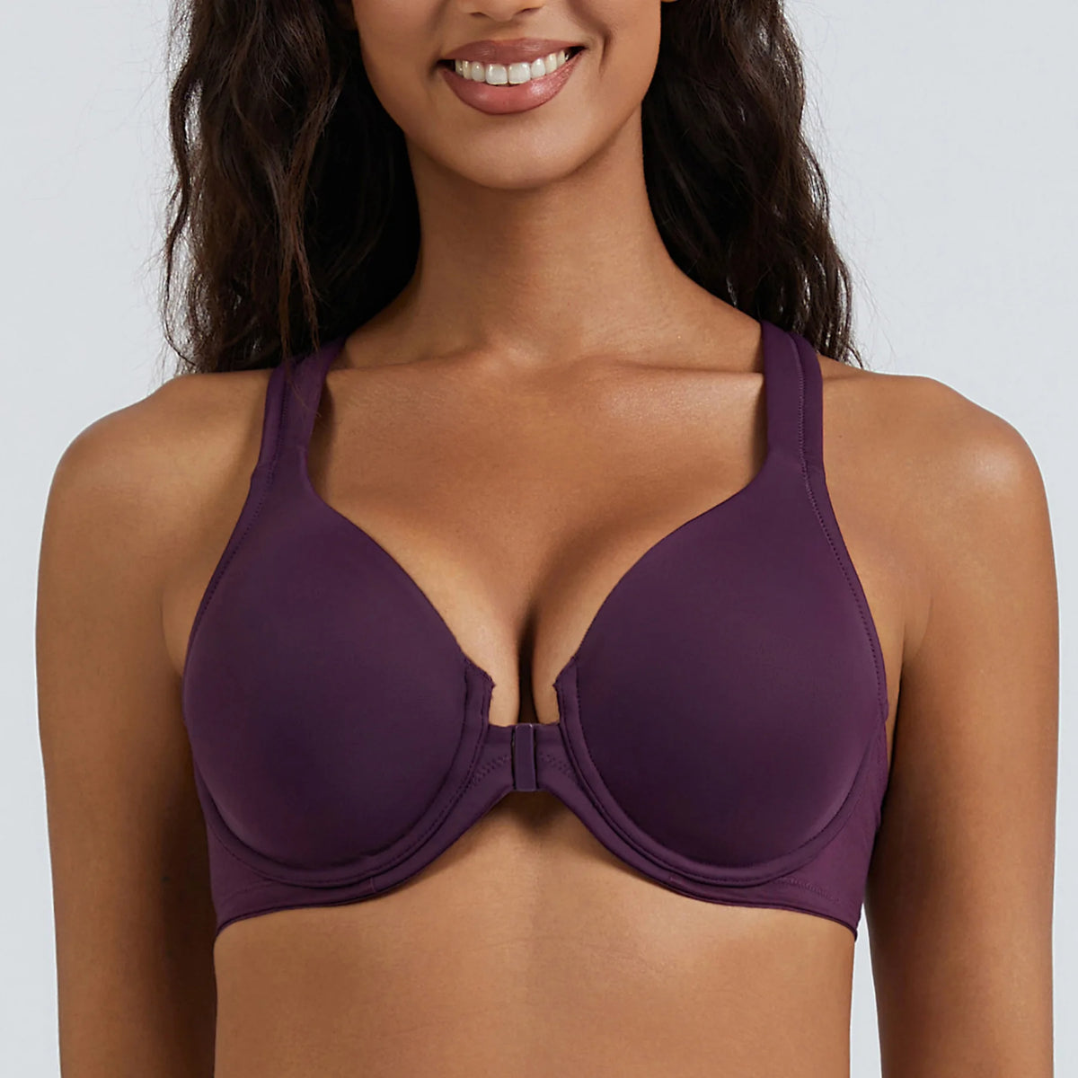 Woman wearing a purple bra against a plain background