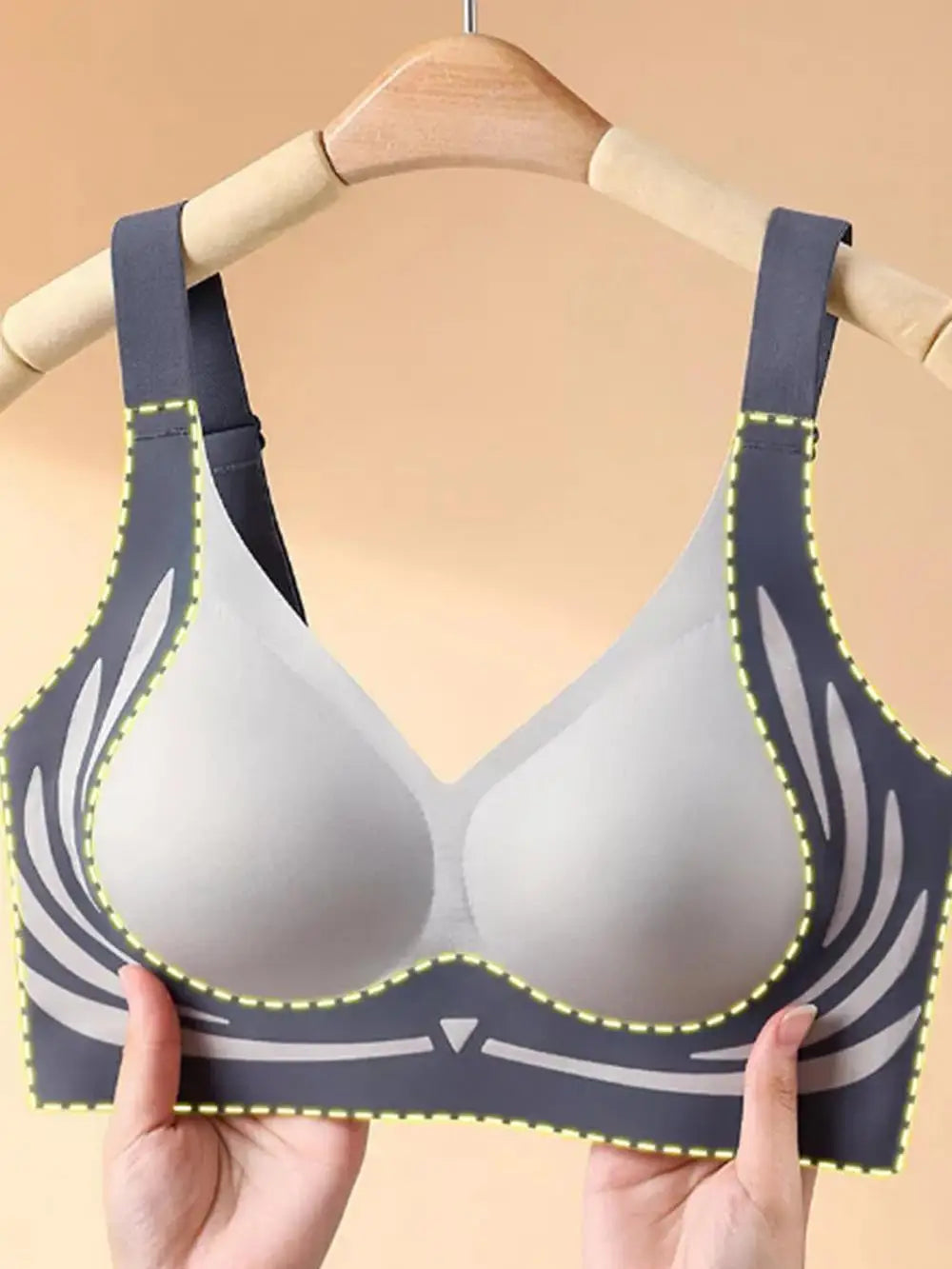 Gray bra with blue straps held by a hand on a beige background
