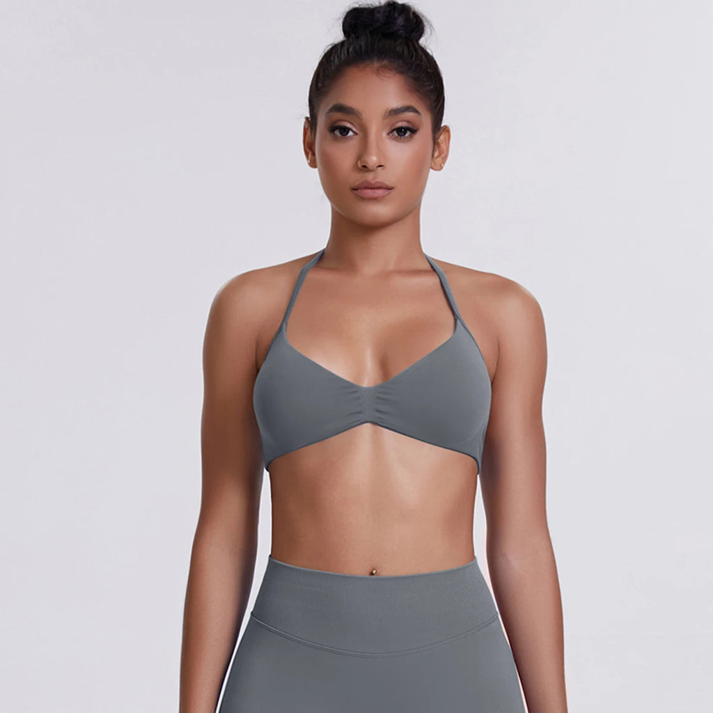 Woman wearing a gray sports bra and leggings on a light gray background