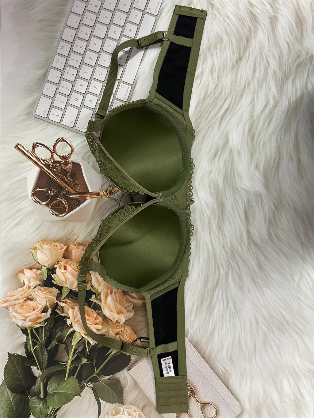 Green bra on a white fur surface with flowers and a keyboard in the background