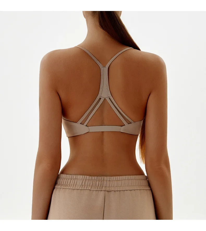 Person wearing a beige strappy top and pants on a white background