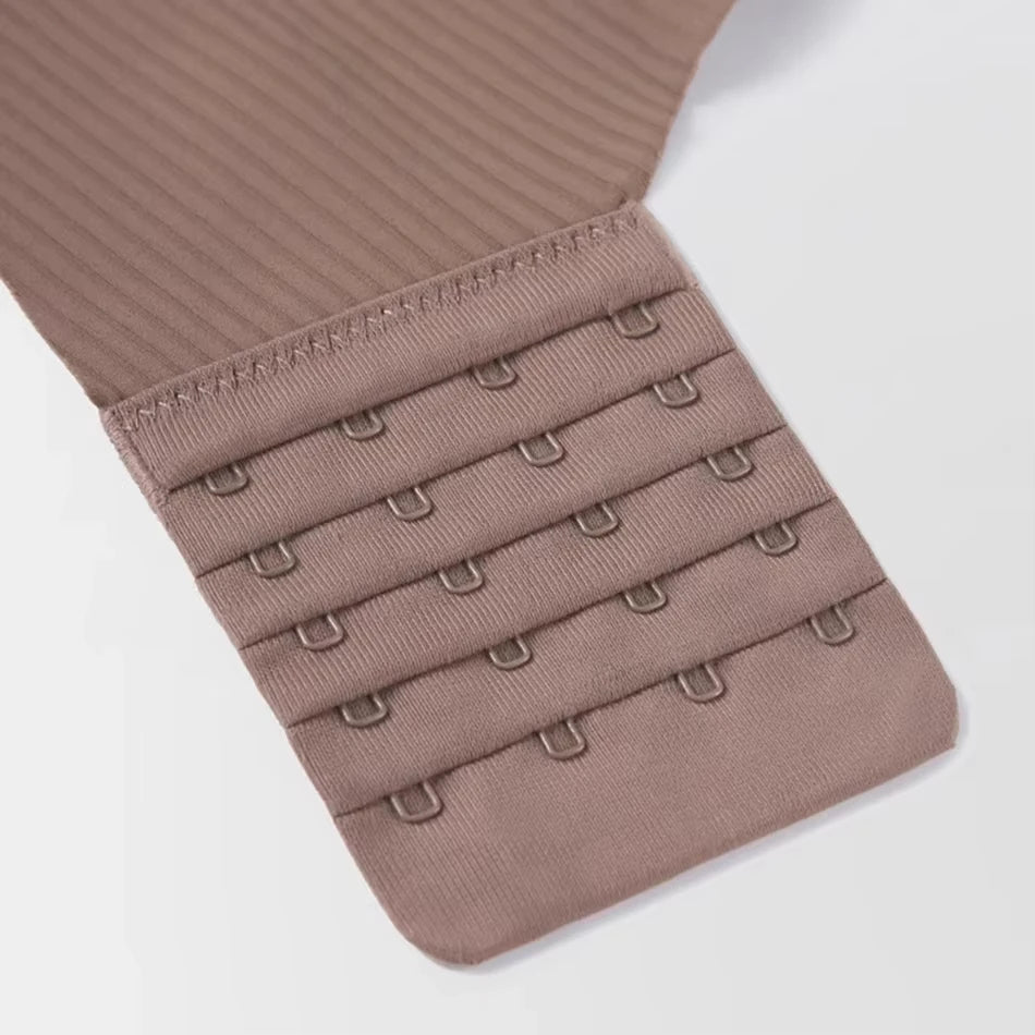 Close-up of a beige bra strap with metal hooks on a light gray background