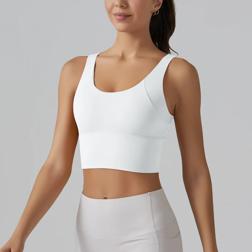 Woman wearing a white sports bra and leggings on a gray background