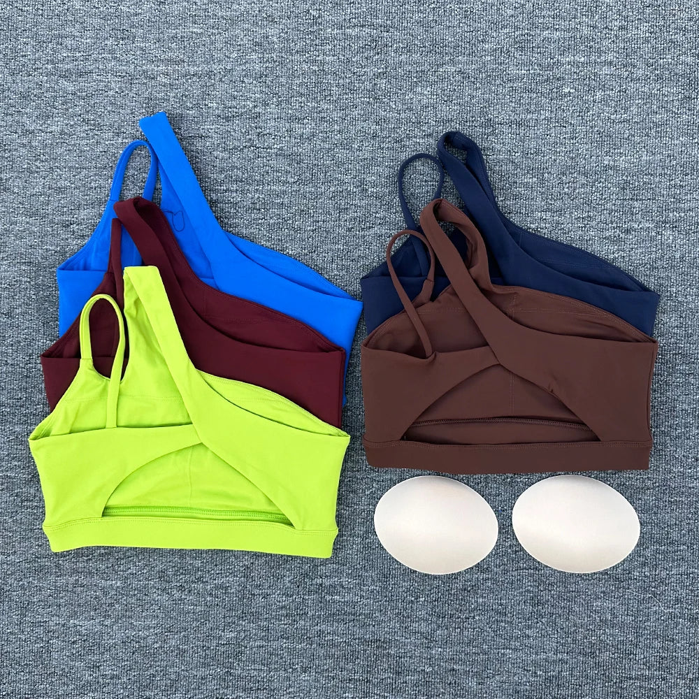 Colorful sports bras and a pair of white cups on a gray textured background