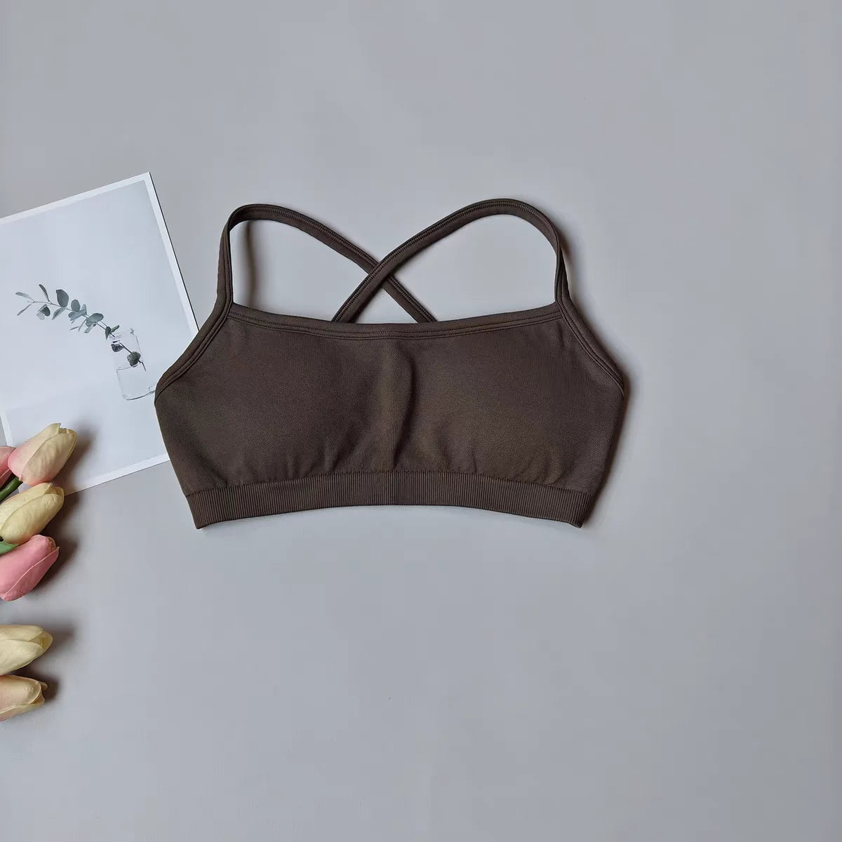 Brown bralette on a gray surface with tulips and a card in the background