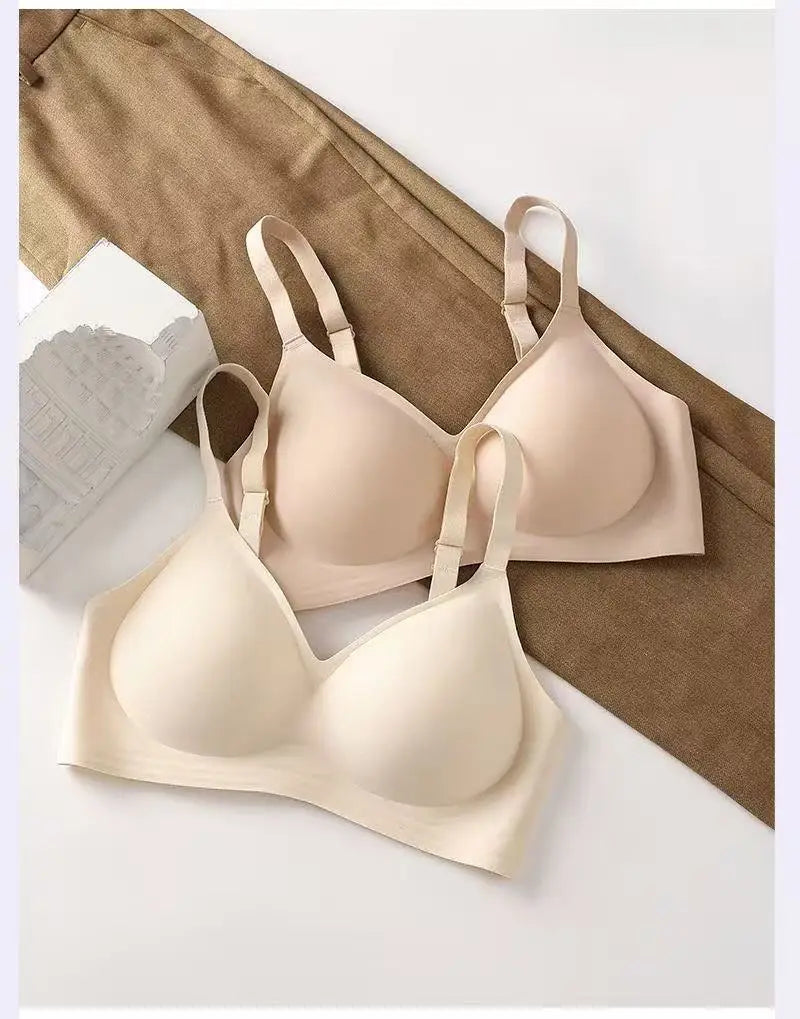 Two beige bras on a white surface with a brown fabric background