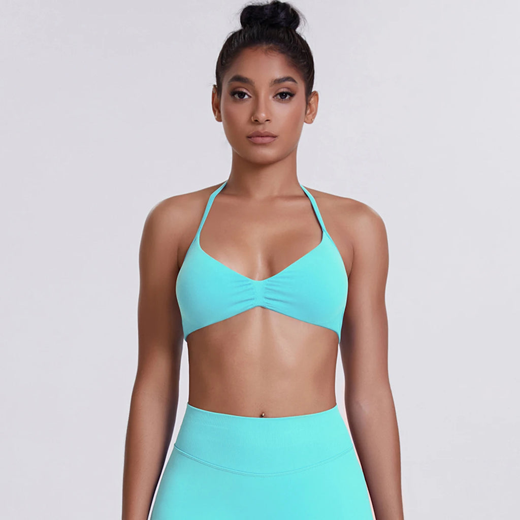 Woman wearing a turquoise sports bra and leggings on a light gray background