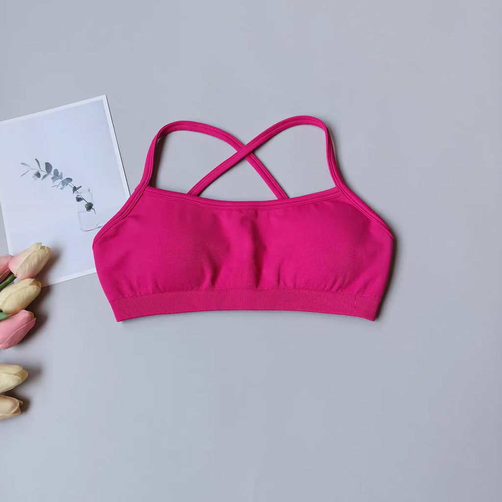 Pink sports bra on a gray surface with a white card and flowers.