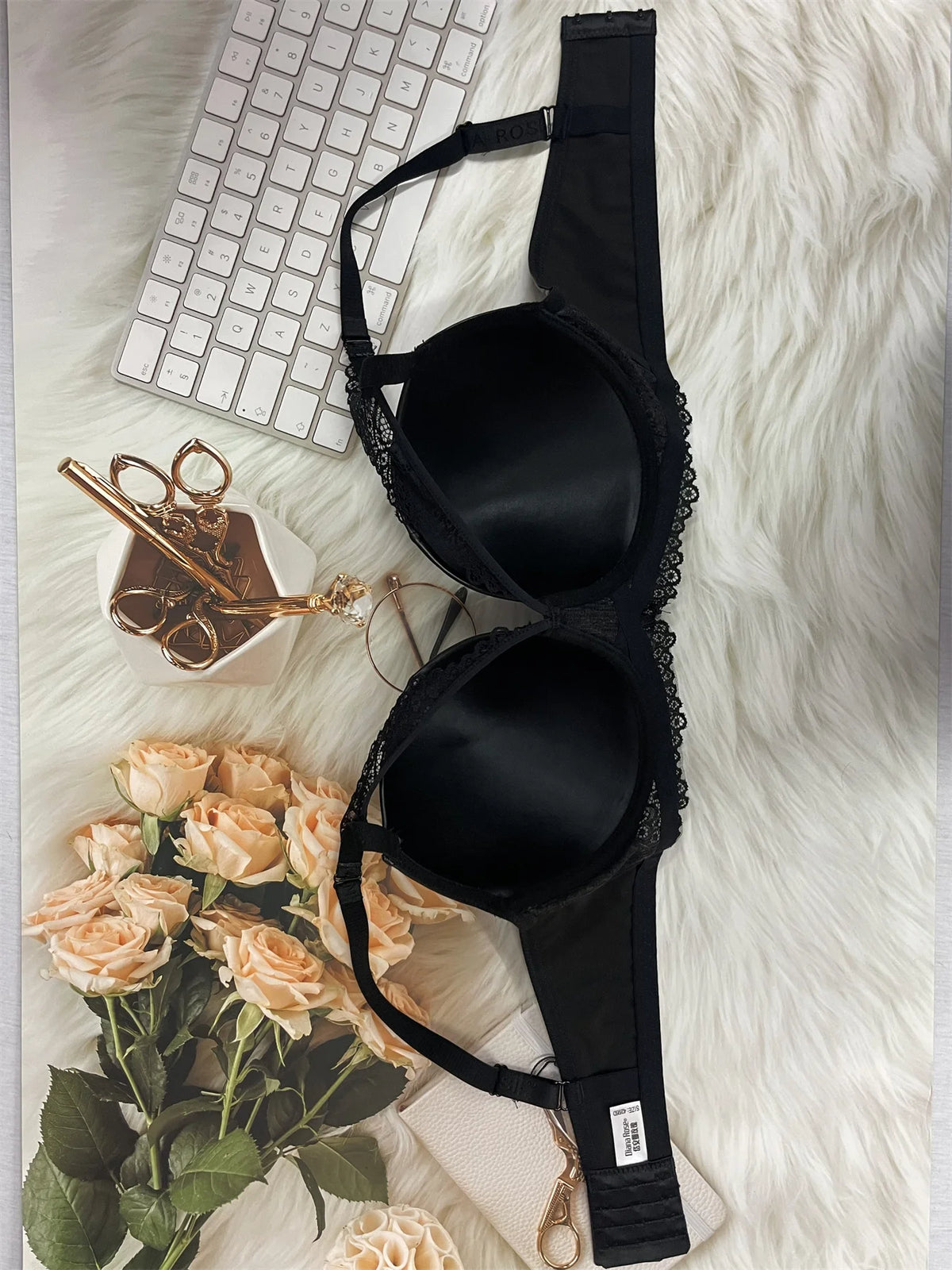 Black bra on a white fur surface with flowers and a keyboard in the background