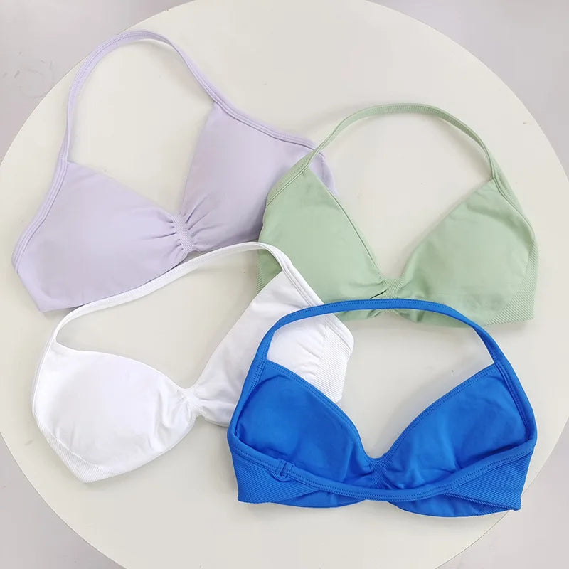 Four bras in different colors (purple, green, white, blue) on a light background