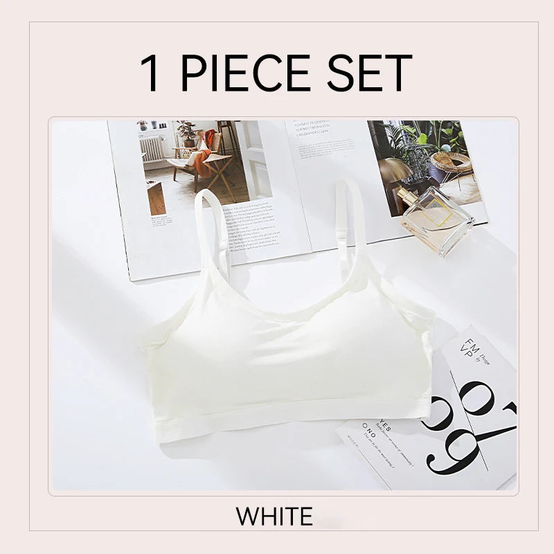 A white one-piece bralette set displayed on a white surface with open magazines as styling props. Text at the top reads '1 PIECE SET' and text at the bottom reads 'WHITE'.