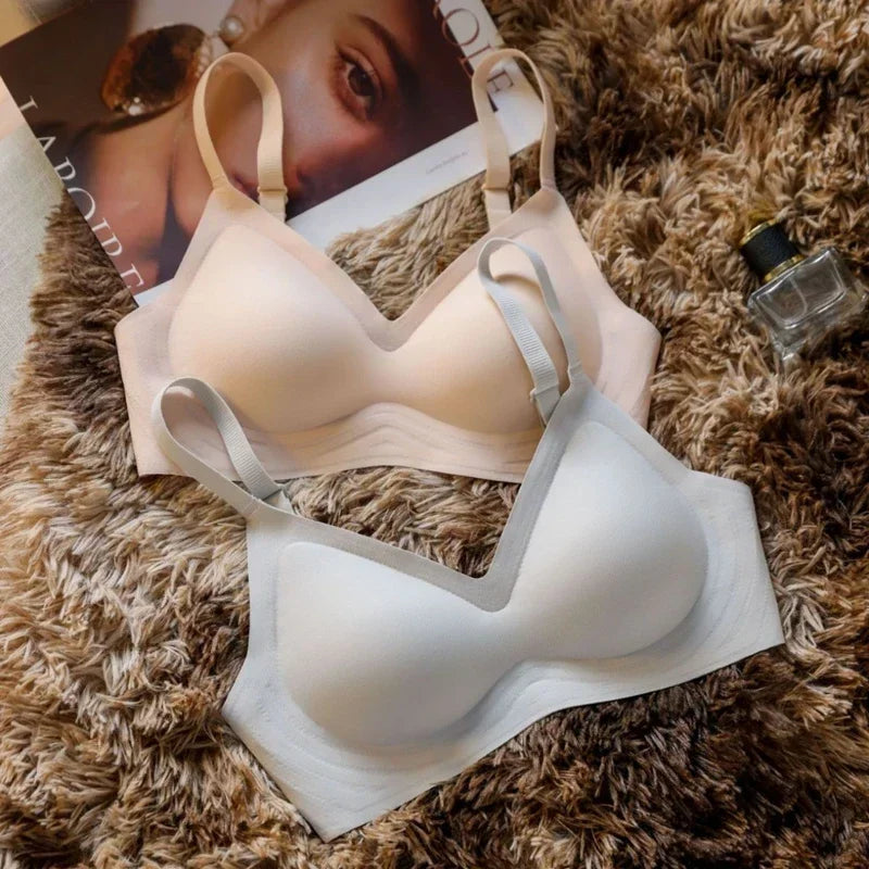Beige bra on a brown textured surface with a magazine and perfume bottle in the background.