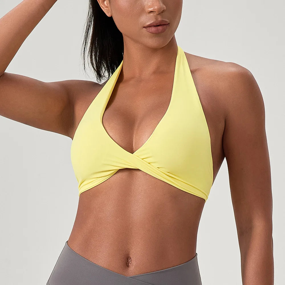 Woman wearing a yellow sports bra and gray leggings on a light gray background