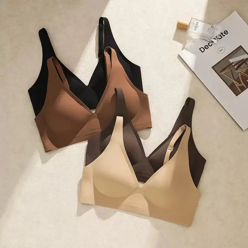 Three bras in black, brown, and beige on a light surface with a magazine in the background.