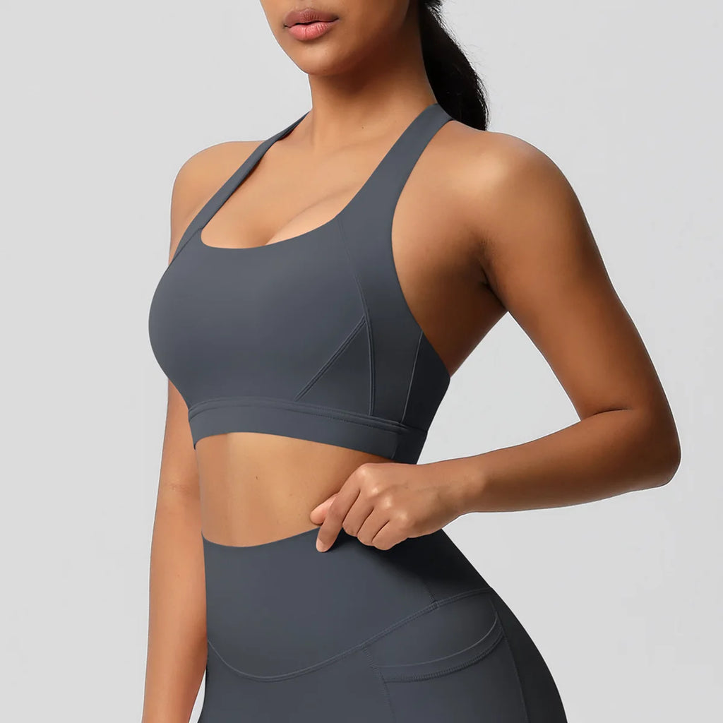 Woman wearing a gray sports bra and leggings on a light gray background