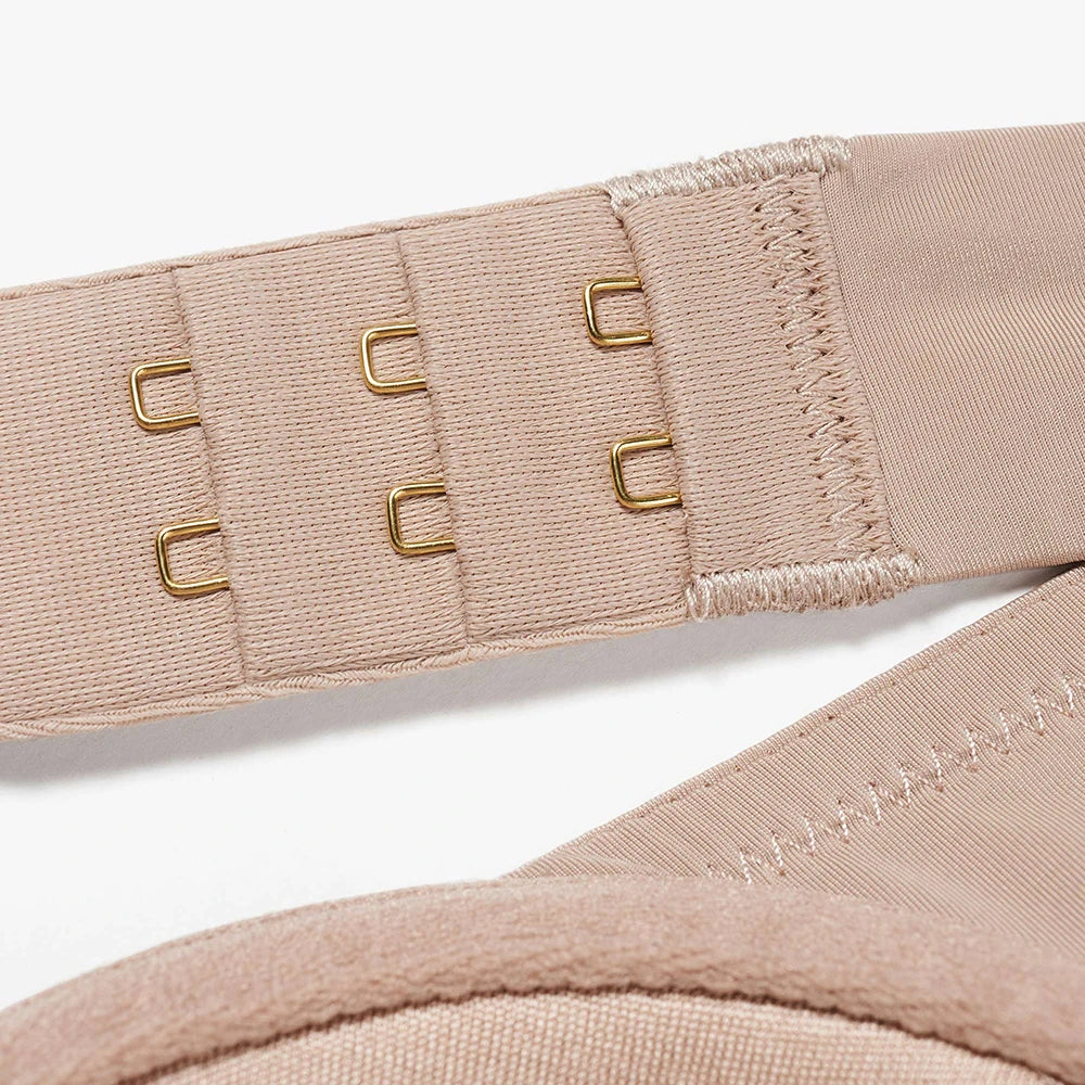 Close-up of a beige bra strap with gold metal adjusters on a white background.