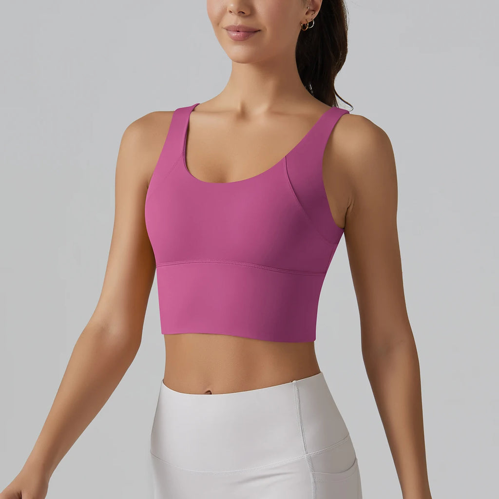 Woman wearing a pink sports bra and white leggings on a gray background