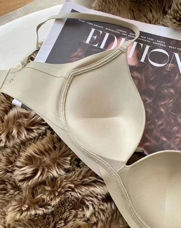 A beige wireless underwire bra laid flat on a magazine page over a brown faux fur surface.